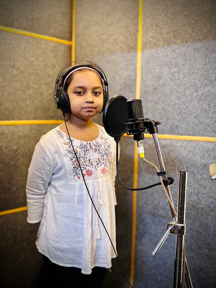 Young singer in studio headphones standing at the microphone